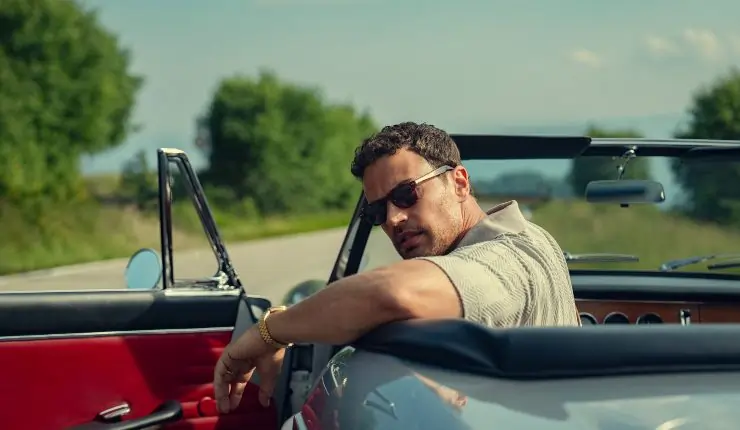 Eddie sits in an roofless car looking for someone or something in The Gentlemen season 2