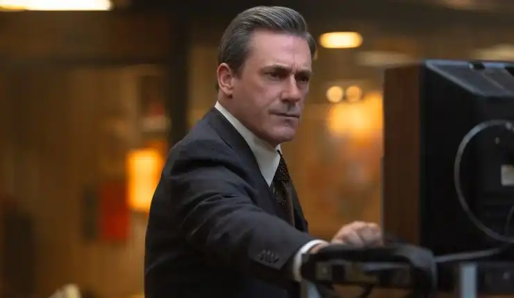 A man in a suite looks at something in American Hostage