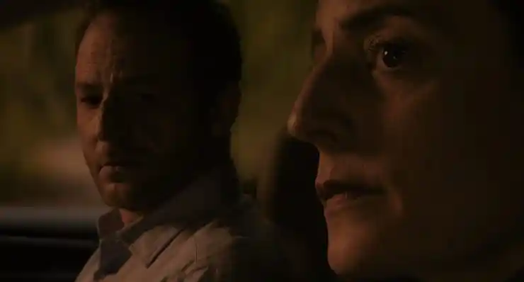 A man and woman sit in a car questioning something
