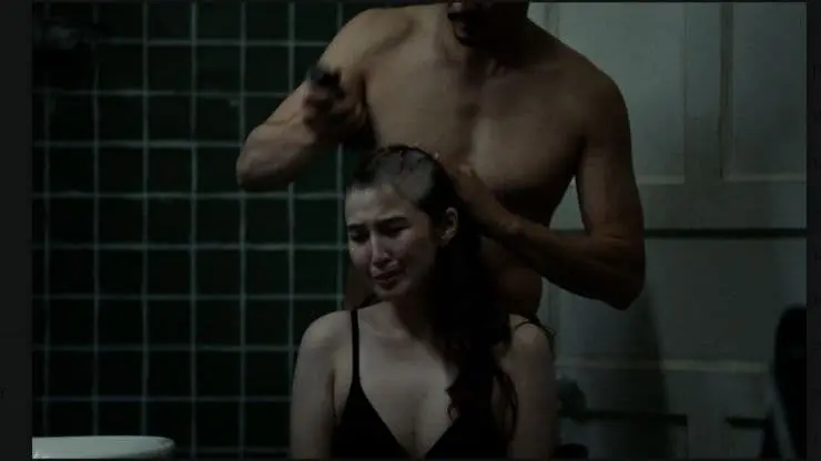 A woman has her head shaved by a man