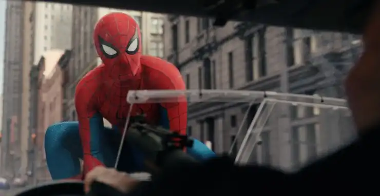 SPider-man takes out a car front window as it moves