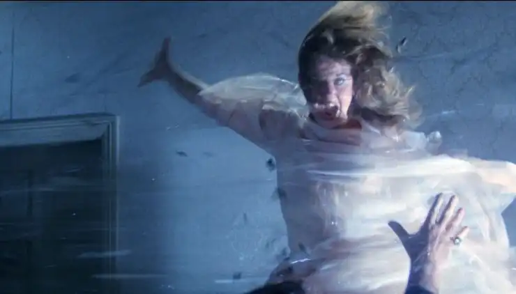 A young woman in white jumps in fear in The Exorcist II: The Heretic