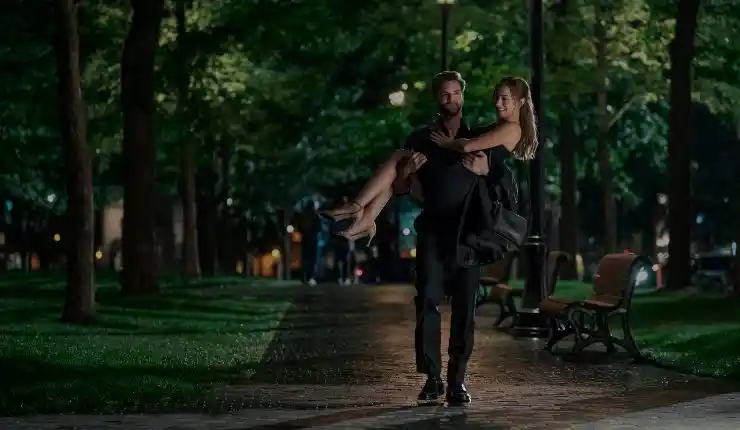 A tall dark and handsome man carries a woman in The Love Hypothesis