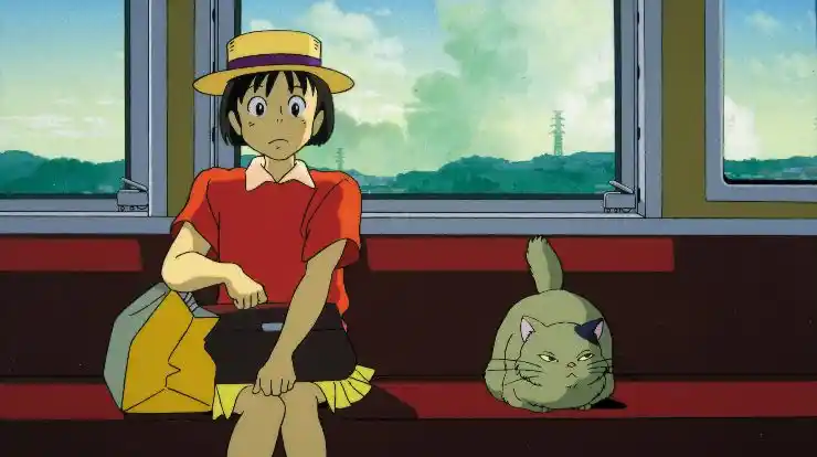 A young animated girl sits on a train with a cat in Whisper Of The Heart