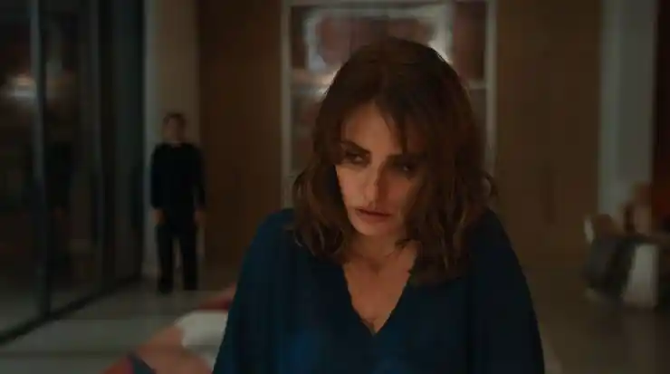 A woman looks shattered as a man stands behind her in kitchen