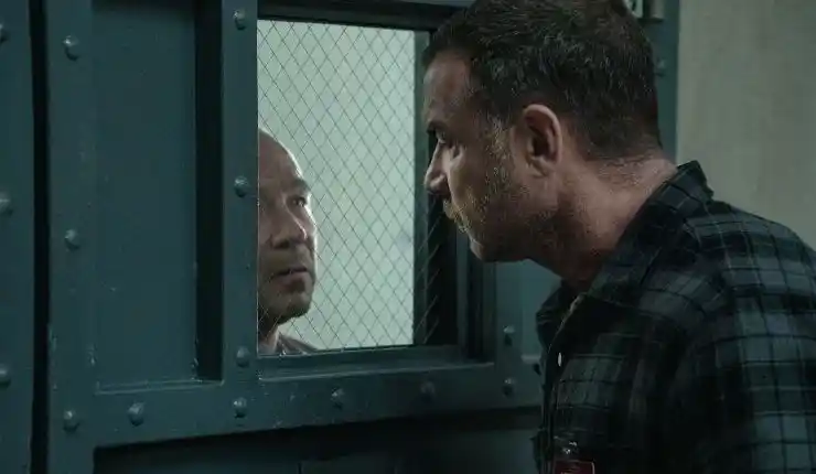 A tall man looks into what looks a prison cell or holding room to another man in Apple TV 's Nocturne