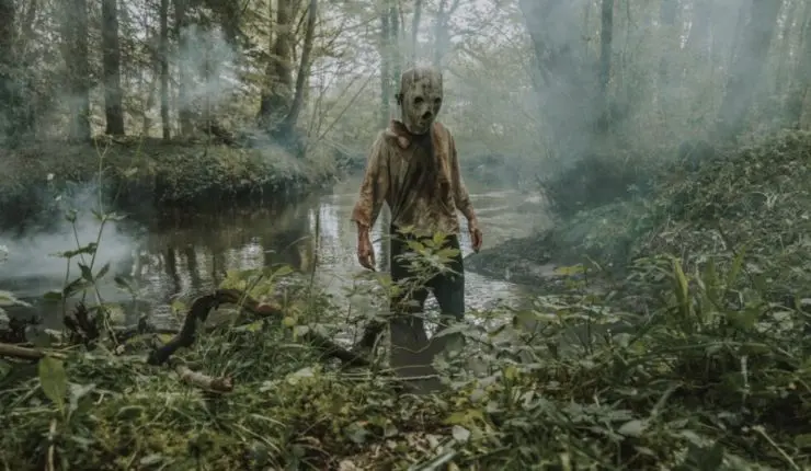 A person in a mask standing in a river