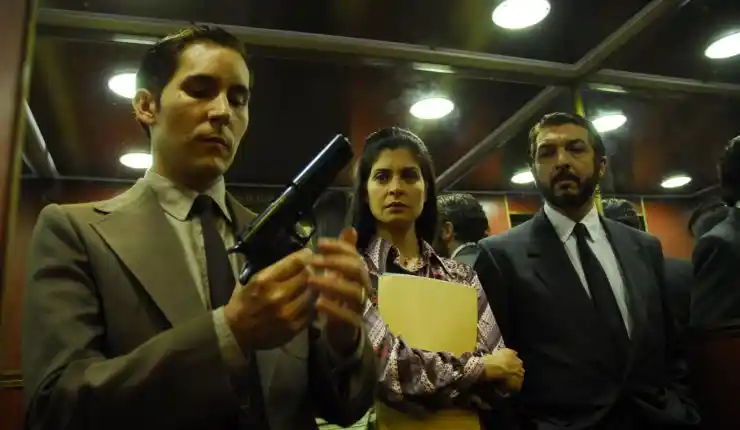 A man glocks a gun as a woman with files and man look on in The Secret In Their Eyes