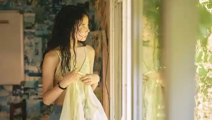 A woman wet hair looks out a window