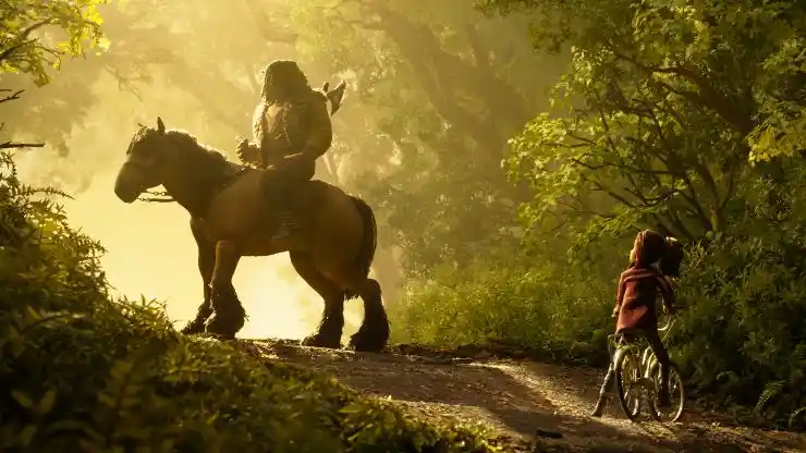 A warrior sits on a horse whilst a young girl awaits