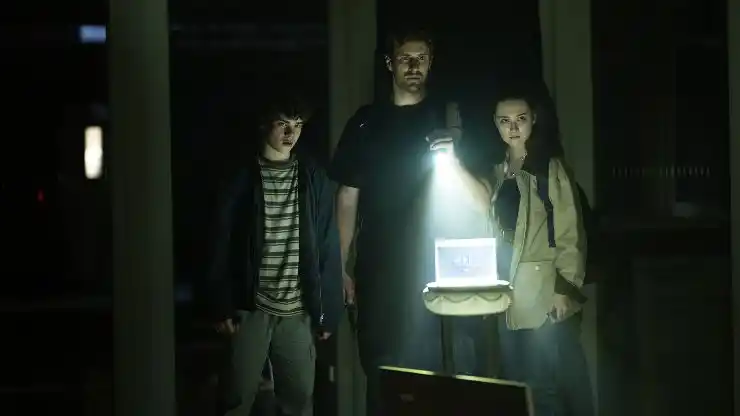 A man stands with his children in the dark with torch in Dead Howling