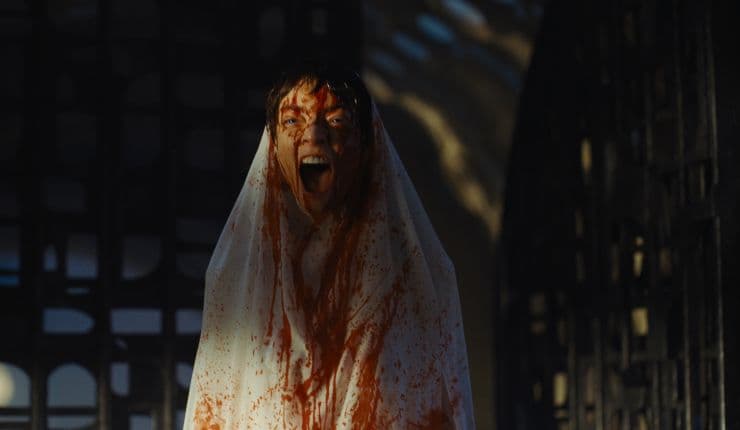 A young woman sprayed with blood looks angry ins Dune: Part Three