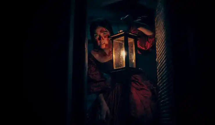 A woman holds a torchlighlight in a darkroom in Marama