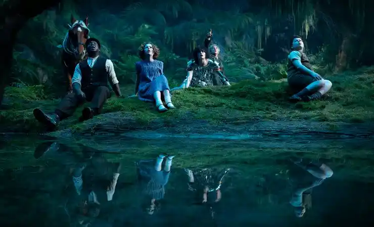 Young people sit next to water in the moonlight in Narnia: The Magician's Nephew